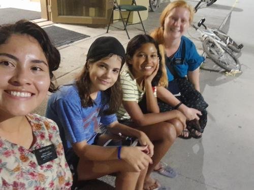 Alyssa and Sister Zurita sitting on the curb with some members