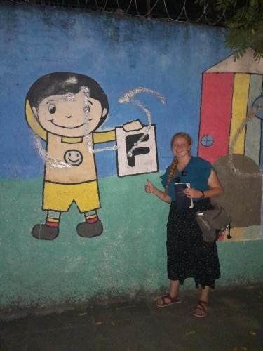 Alyssa gives a thumbs up next to a mural boy who got an F