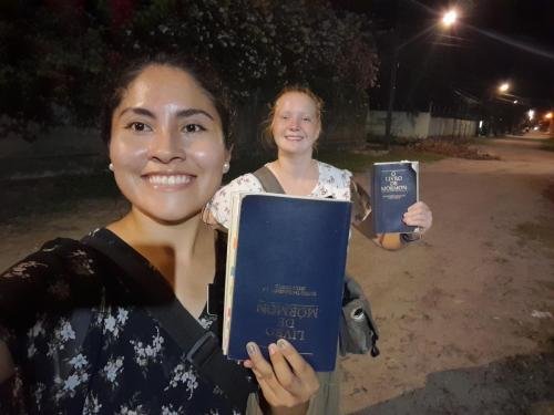 Alyssa and Sister Zurita holding Books of Mormon on a dirt road