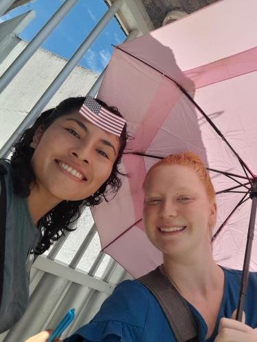 Alyssa with Sister Zurita with a US flag on her head under an umbrella