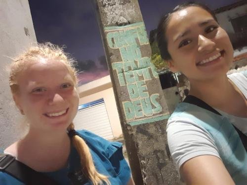 A selfie of Alyssa and Sister Quispe by a pole with graffiti about God