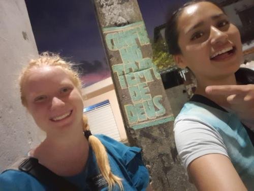 A selfie of Alyssa and Sister Quispe by a pole with graffiti about God