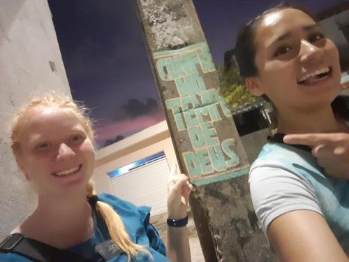 A selfie of Alyssa and Sister Quispe by a pole with graffiti about God