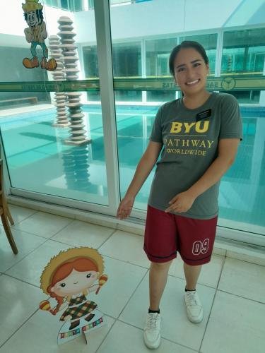 Sister Quispe with a cutout, cardboard, maraca playing doll