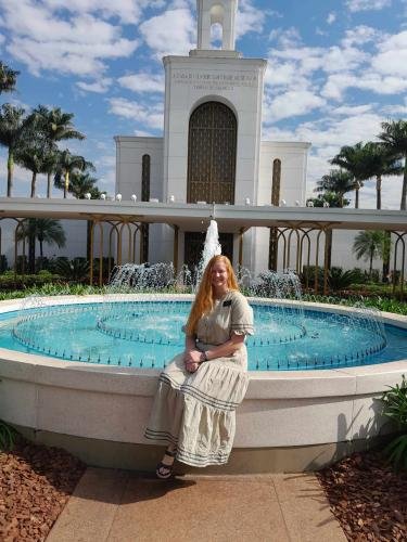 Alyssa sitting on the edge of the pool in front of the Sao Paulo temple